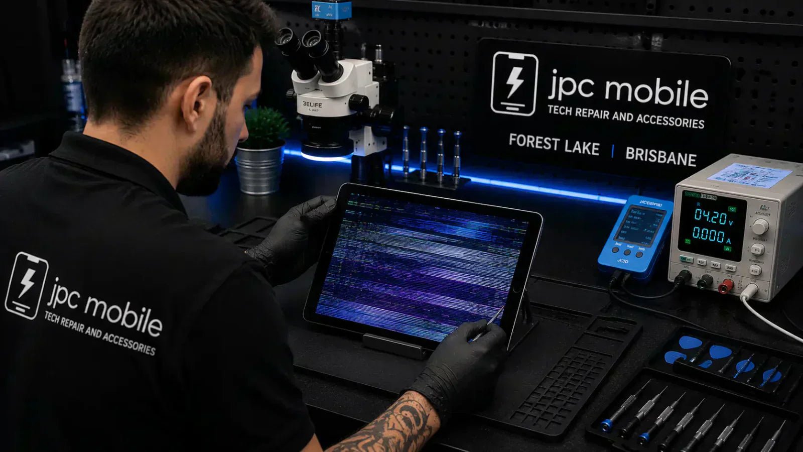 Technician diagnosing an iPad with a flickering display problem at a professional repair workstation